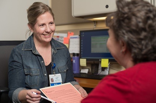 Photo of two people smiling and talking about patient forms